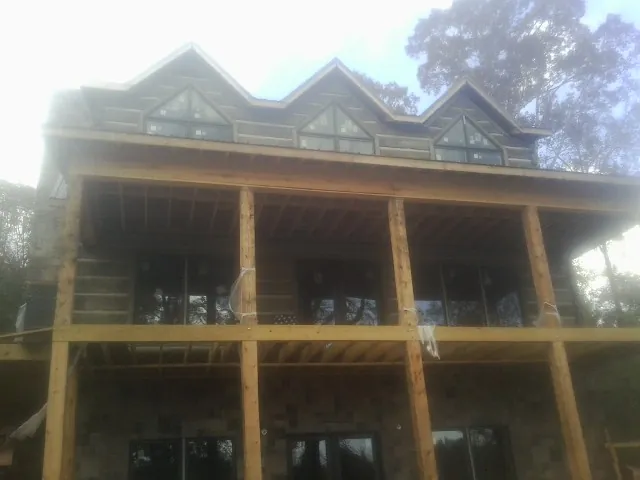 Dormers and porch framing on a large log home under construction — Roof Coating work by our crew in New Carlisle