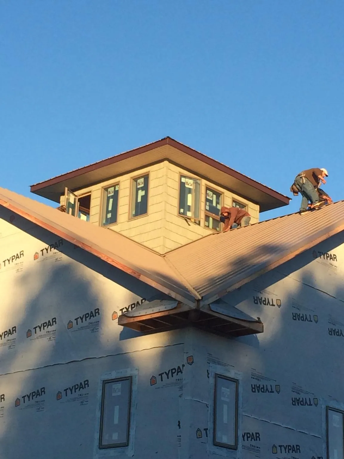 Roofers working around a rooftop cupola on a new metal roof at sunset — Roof Waterproofing in New Carlisle by Roofing Brothers